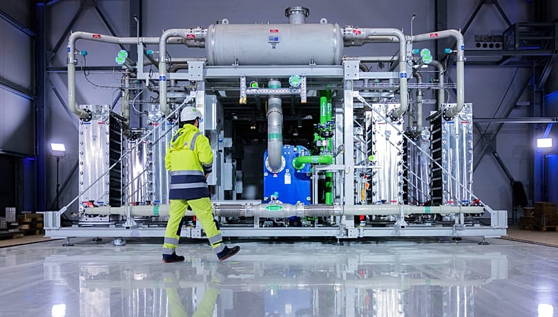 A worker walks in front of a electrolyzer for the production of green hydrogen at the Air Liquide company in Oberhausen, Germany, Tuesday, May 2, 2023.