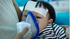Eine Frau hilft einem Baby beim Inhalieren mit einem Vernebler.