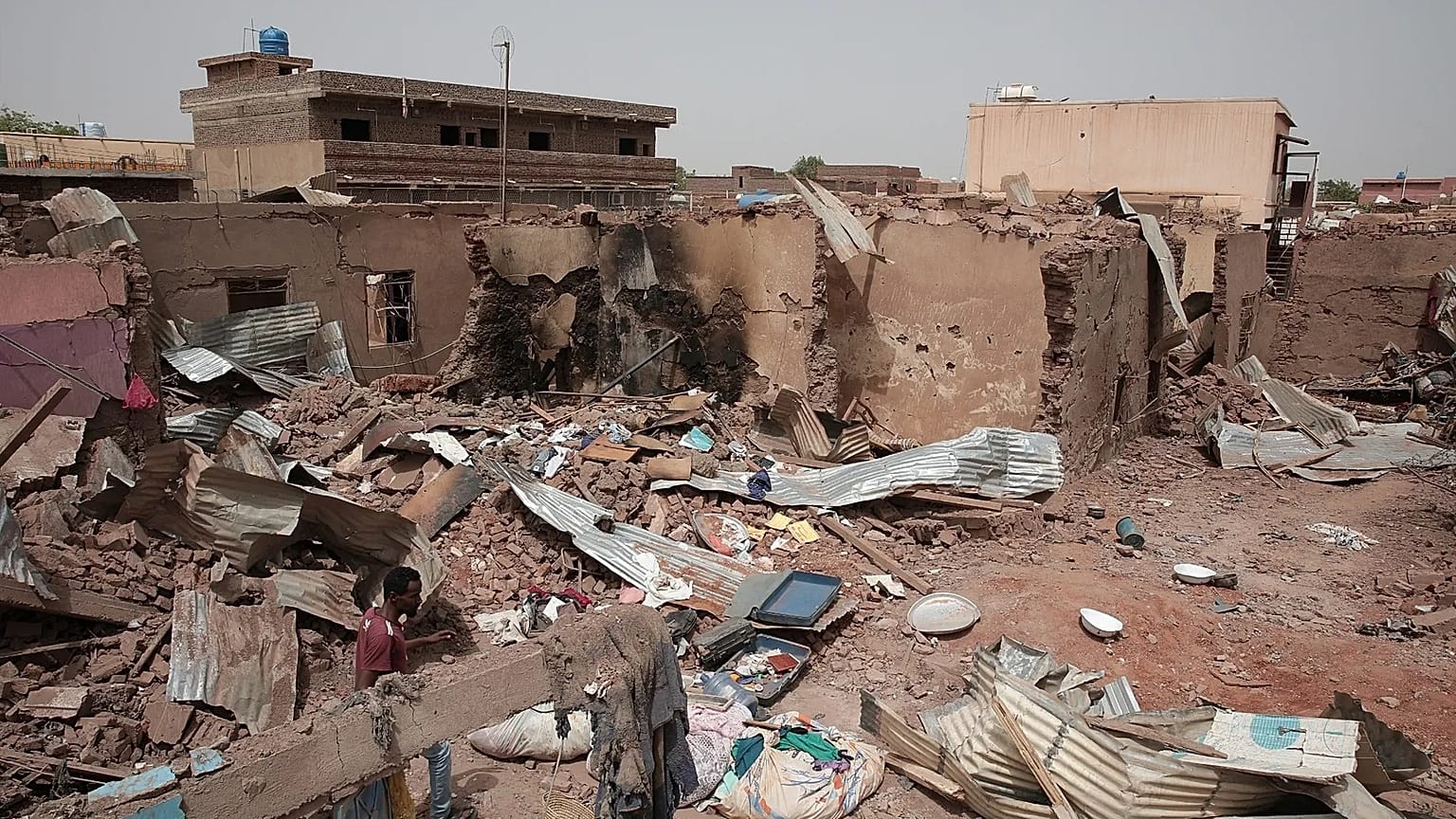 A man walks by a house hit in recent fighting in Khartoum, Sudan, an area torn by fighting between the military and the notorious paramilitary Rapid Support Forces.