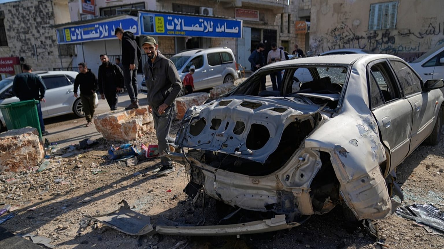 سكان يتفقدون مركبة مدمّرة بعد مداهمة للجيش الإسرائيلي أسفرت عن مقتل فلسطيني في بلدة قباطية بالضفة الغربية، في 20 نوفمبر 2025.