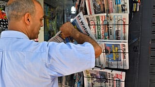 صورة تعبيرية لبائع متجول يعرض أعدادًا من صحيفة الوطن في الجزائر