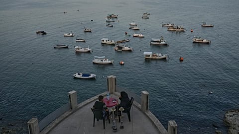 A Syrian couple smokes hookah at Latakia's Mediterranean seaside corniche, in the coastal city of Latakia, 3 October 2025