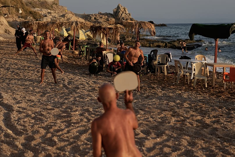 Syrian sunbathers play racquetball at a public beach on the Mediterranean Sea, in Latakia, 8 October 2025