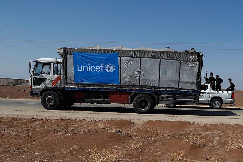FILE: Members of Syrian government security forces stand on a vehicle as they pass by a truck carrying UN humanitarian aid on his way toward Suweyda, 28 August 2025