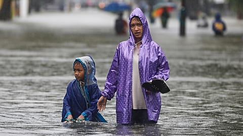 Persone guadano nell'acqua in una strada allagata a Medan, in Sumatra Settentrionale, Indonesia