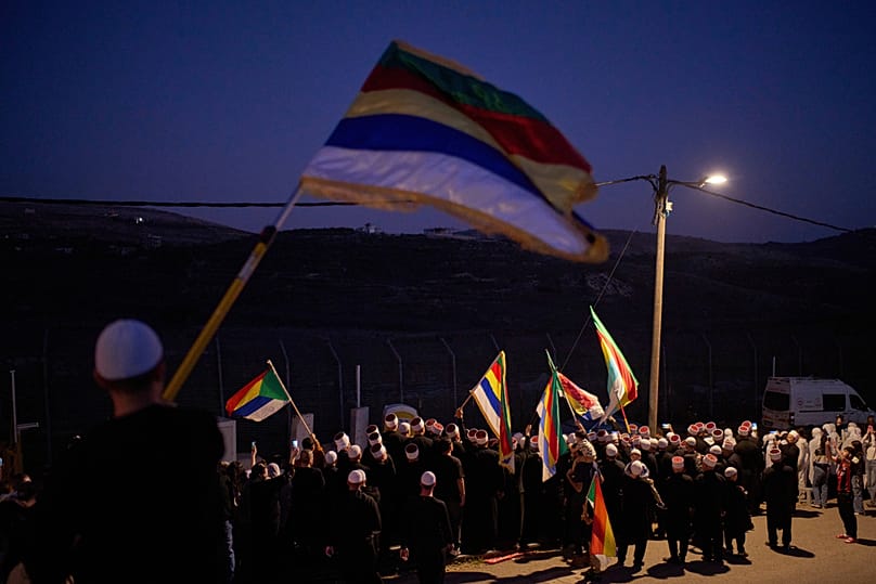  أبناء الطائفة الدرزية في بلدة مجدل شمس يلوحون بالأعلام لوداع رجال الدين الدروز السوريين، قبل عبورهم الحدود عائدين إلى سوريا، مرتفعات الجولان، السبت15 مارس/آذار 2025