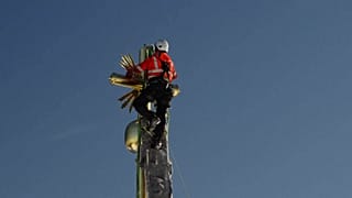 Climber securing the cross atop snowy Zugspitze peak