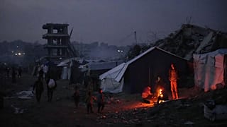 يقف فلسطينيون نازحون قرب نار أوقدوها بجانب خيمتهم وسط الدمار الذي خلّفته العملية الجوية والبرية في مدينة غزة، الجمعة 28 نوفمبر/تشرين الثاني 2025. (أ ب / عبد الكريم هنا)