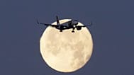A TAP Air Portugal Airbus A320 is silhouetted against the setting moon while approaching for landing in Lisbon, Portugal, June 23, 2024. 