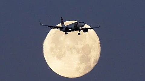 A TAP Air Portugal Airbus A320 is silhouetted against the setting moon while approaching for landing in Lisbon, Portugal, June 23, 2024. 