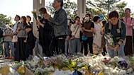 Emberek imádkoznak és virágokat helyeznek el a szerdai halálos tűzvész helyszínénél