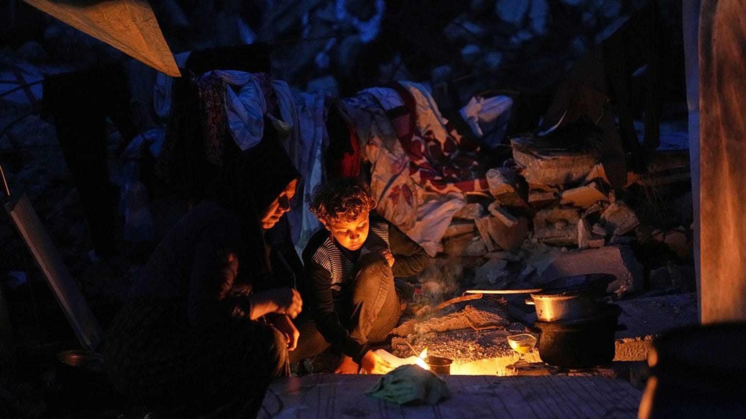 نازحة فلسطينية وابنها يطبخان على النار أمام خيمتهما في مدينة غزة الجمعة 28 نوفمبر 2025
