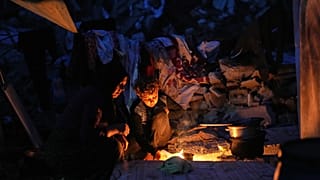 نازحة فلسطينية وابنها يطبخان على النار أمام خيمتهما في مدينة غزة الجمعة 28 نوفمبر 2025