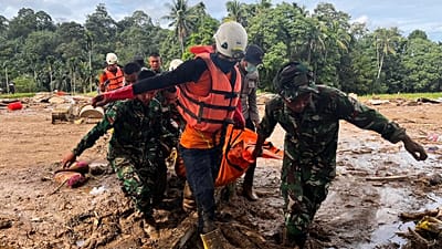 Rescuers carry the body of a flood victim, in Agam, West Sumatra, Indonesia, Sunday, Nov. 30