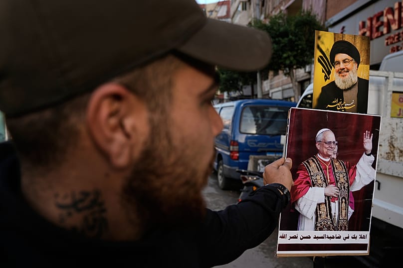 يحمل أحد أنصار حزب الله صورًا لأمين العام الراحل حسن نصرالله أثناء ترحيبه بالبابا لاوون الرابع عشر في بيروت، لبنان، يوم الأحد، 30 نوفمبر 2025.