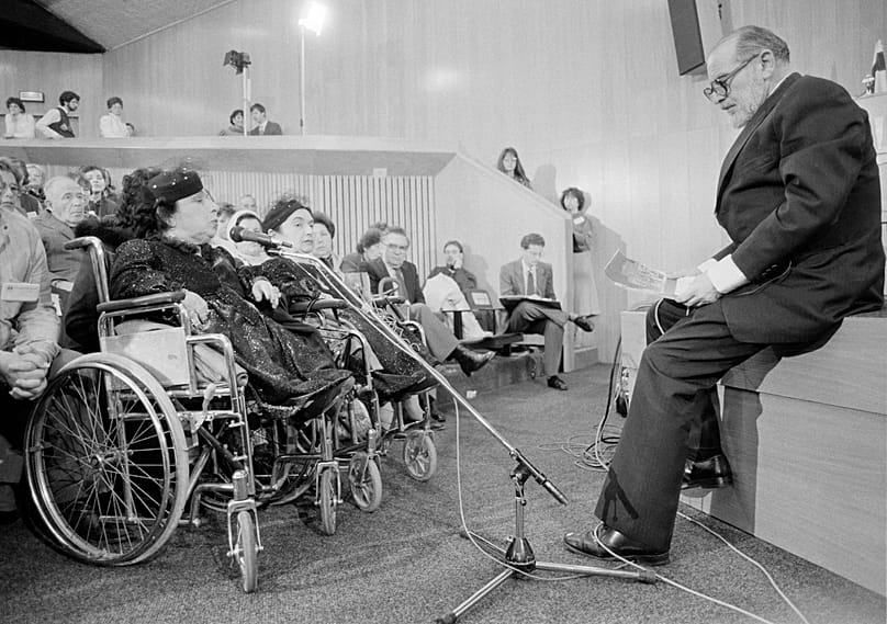 الیزابت و سارا موسکوویتچ، دوقلوهای کوتاه‌قامت ۵۹ ساله و تنها بازماندگان از میان دوقلوهای مورد آزمایش منگله، در جریان شبیه‌سازی دادگاه او در بیت‌المقدس در سال ۱۹۸۵