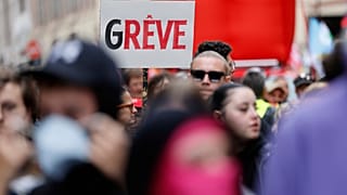 Um manifestante segura um cartaz de "Greve" durante um protesto contra os cortes orçamentais em Lille, na quinta-feira, 18 de setembro de 2025.