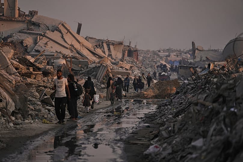 فلسطينيون يسيرون وسط الدمار الذي خلّفته الحرب الإسرائيلية حي الشيخ رضوان بمدينة غزة، في 10 نوفمبر 2025.