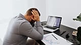Un uomo è stressato davanti al suo computer portatile.