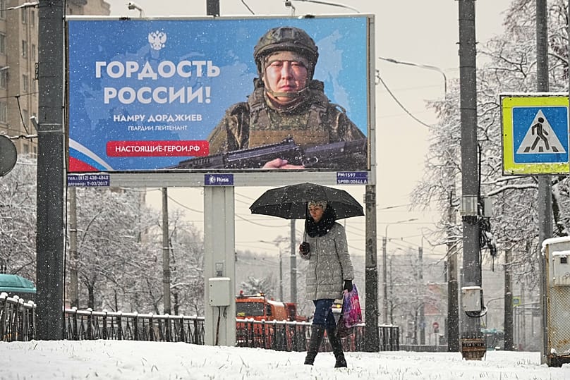 A person walks past a billboard showing a Russian soldier participating in military action in Ukraine reading "The pride of Russia" in St. Petersburg, 24 November, 2025