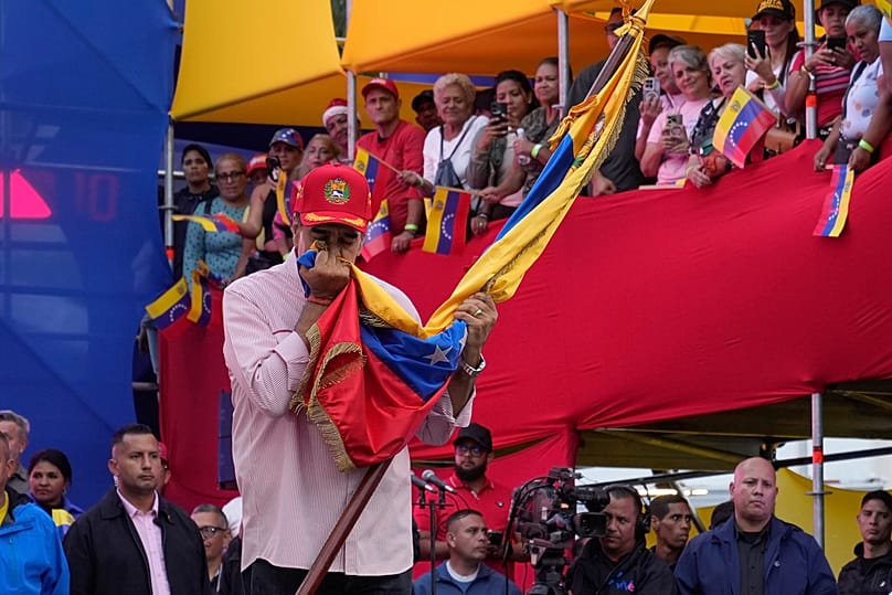 Maduro besa una bandera venezolana durante un acto de juramento de los comités comunitarios organizados por el Gobierno en Caracas el lunes 1 de diciembre de 2025.