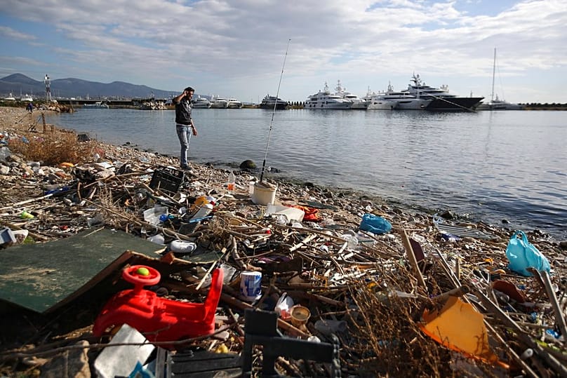 رجل يصطاد على شاطئ نيو فالايرو جنوبي أثينا، حيث يغطي النفايات البلاستيكية الساحل.