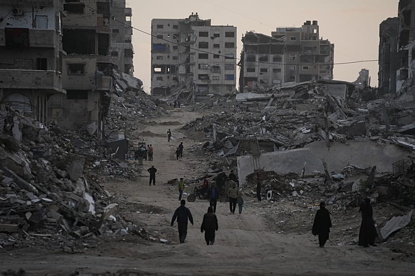 Palestinians walk through the destruction in the Al-Karama neighbourhood of Gaza City, 30 November, 2025