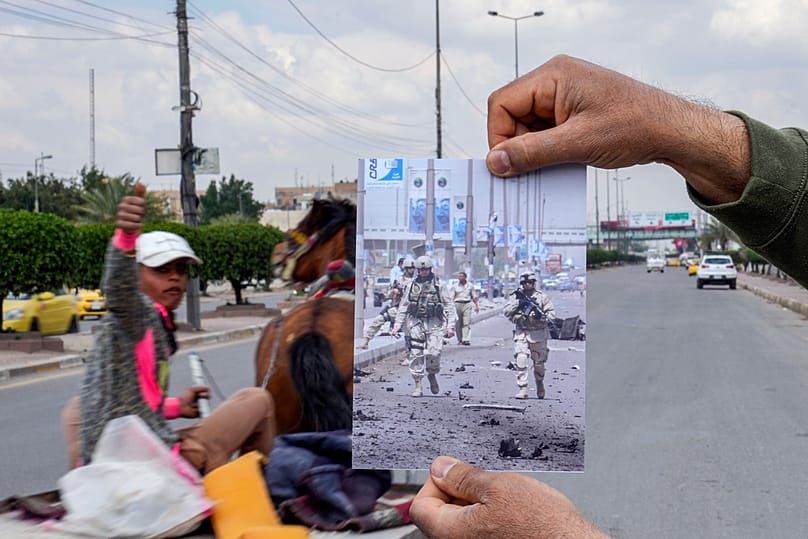 صورة لجنود أمريكيين في موقع انفجار سيارة مفخخة ببغداد، أُعيد وضعها في المكان نفسه في 21 آذار/ مارس 2023 بعد عشرين عامًا على الغزو الأمريكي للعراق.