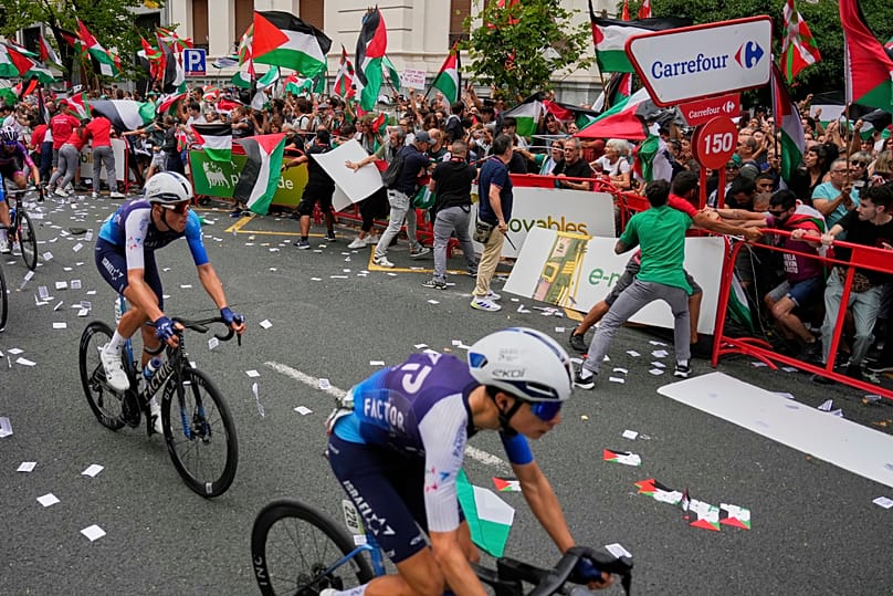 Los ciclistas de Israel Premier Tech compiten mientras personas con banderas palestinas intentan interrumpir la etapa de la Vuelta a España, España, el 3 de septiembre de 2025