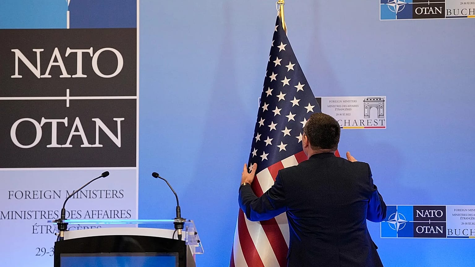 A man sets up a US flag before former United States Secretary of State Antony Blinken's press conference in Bucharest, 30 November, 2022