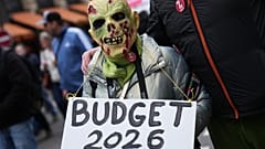 Bir protestocu, Paris'te kemer sıkma politikalarına karşı düzenlenen bir gösteride "Bütçe 2026" yazılı bir pankart tutarken, 2 Aralık 2025