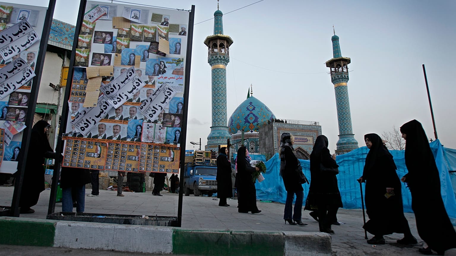 يمرّ إيرانيون بجانب ملصق انتخابي مغطى بملصقات لمرشحين مختلفين قبل يومين من الانتخابات البرلمانية الإيرانية، يوم الأربعاء 29 فبراير/شباط 2012، في شمال طهران. 