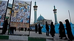يمرّ إيرانيون بجانب ملصق انتخابي مغطى بملصقات لمرشحين مختلفين قبل يومين من الانتخابات البرلمانية الإيرانية، يوم الأربعاء 29 فبراير/شباط 2012، في شمال طهران. 