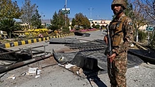 يقف جندي بالجيش على الحراسة بجانب الأضرار عند البوابة الرئيسية لكلية الكُدَّات التي تُدار من قبل الجيش