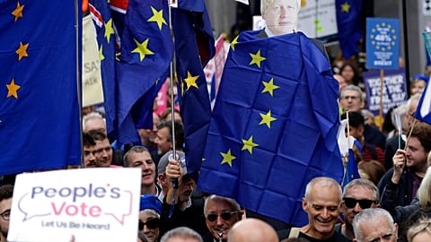 FILE - Anti-Brexit remain in the European Union supporters hold with former Prime Minister Boris Johnson draped in an EU flag as they demand another Brexit vote. 2019 