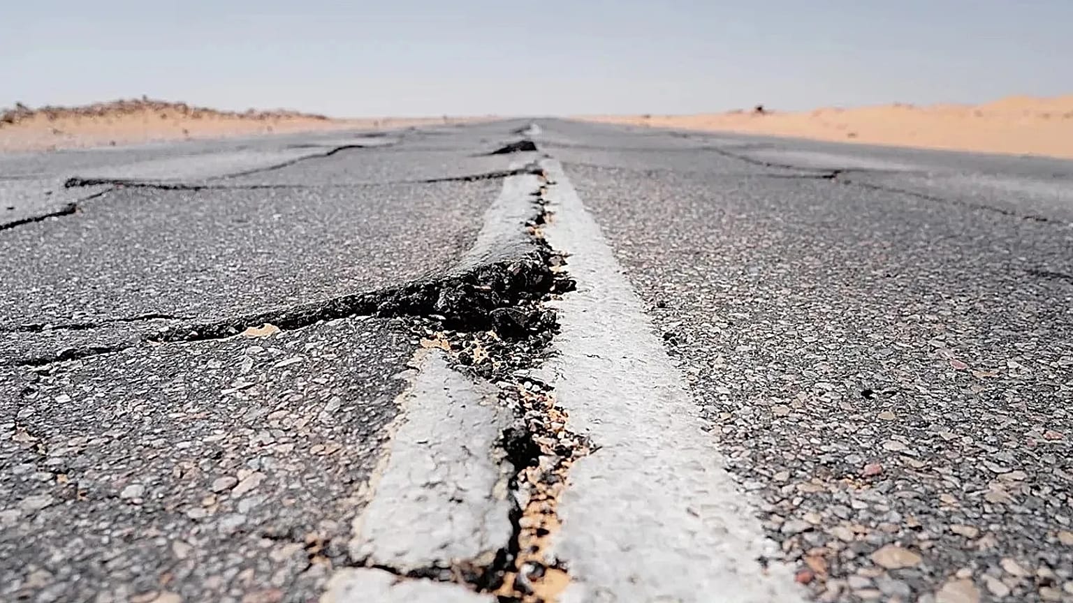 Bu stok fotoğrafta bir kara yolunda deprem sonrası yarıklar oluştuğu görülüyor.