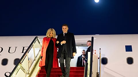 En esta foto difundida por la agencia de noticias Xinhua, el presidente de Francia, Emmanuel Macron, y su esposa, Brigitte Macron, bajan del avión a su llegada a Pekín.