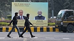 يمرّ رجال بجوار لوحة إعلانية تحمل صورًا لرئيس الوزراء الهندي ناريندرا مودي، على اليمين، والرئيس الروسي فلاديمير بوتين، قبل ساعات من وصول الأخير المقرر إلى نيودلهي، الهند، 