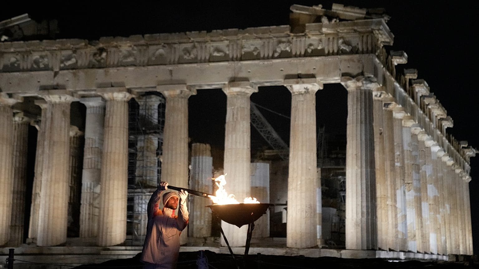 Olympic gold medallist rower Stefanos Ntouskos lights a cauldron with the Olympic flame by the Parthenon during the Milan Cortina 2026 torch relay in Athens on Dec. 3, 2025.