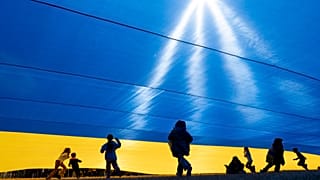 FILE: Children play under an Ukrainian flag as demonstrators rally in support of Ukraine at The Ellipse near the White House in Washington, Saturday, March 8, 2025
