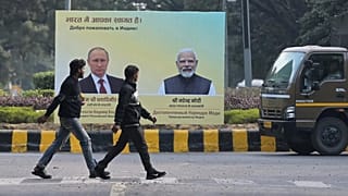 İnsanlar, Vladimir Putin ile Narendra Modi'nin fotoğraflarının yer aldığı afişin önünde yürüyor, 4 Aralık 2025