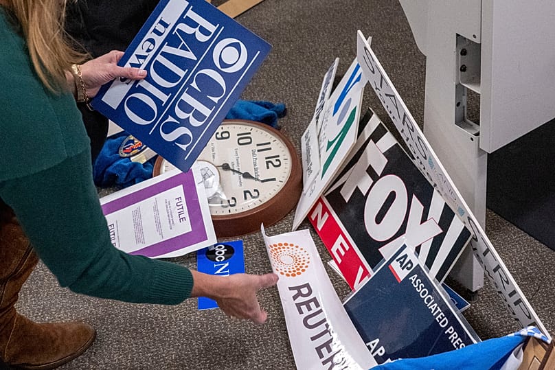 A Washington Post reporter saves the name plaques from various news organisations as she and members of the media leave the Pentagon press area, 15 October, 2025 