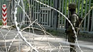 A soldier stands guard by a metal barrier in Bialowieza forest, 29 May 2024
