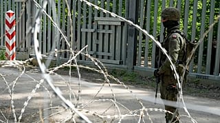 A soldier stands guard by a metal barrier in Bialowieza forest, 29 May 2024
