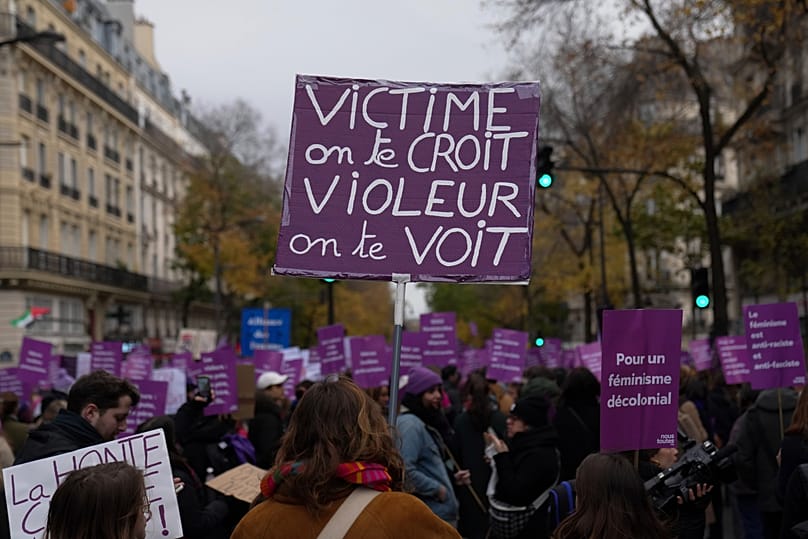 A protestor holds a placard reading "Victim we believe you. Rapist we see you" during a march in Paris, 23 November, 2024