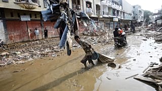 A survivor drags a sack of salvaged items through the mud at an area affected by flash flood in Aceh Tamiang, on Sumatra Island, Indonesia, Thursday, Dec. 4, 2025.