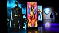 FILE - A visitor walks past portraits of DC Comics superheroes as she enters the "Action and Magic Made Here" interactive experience at the Warner Bros. Studio Tour Hollywood.