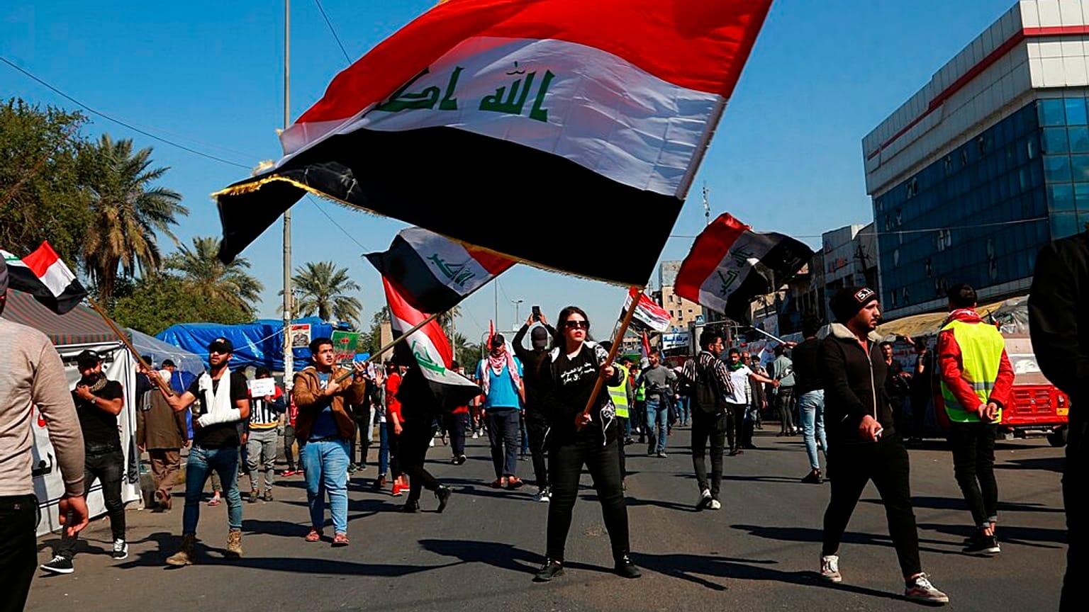 طلاب ومتظاهرون آخرون يرفعون أعلامًا وطنية خلال احتجاج في ساحة التحرير ببغداد، العراق، الخميس 6 فبراير/شباط 2020.