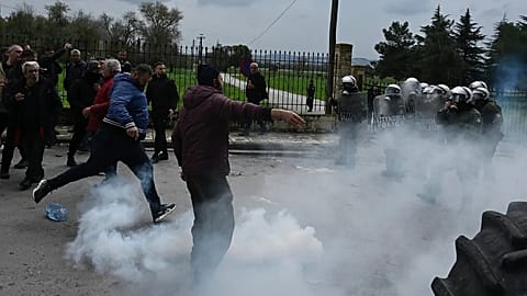 A man kicks a tear gas cannister back toward riot police during clashes near the access road to Thessaloniki's international airport, 5 December, 2025