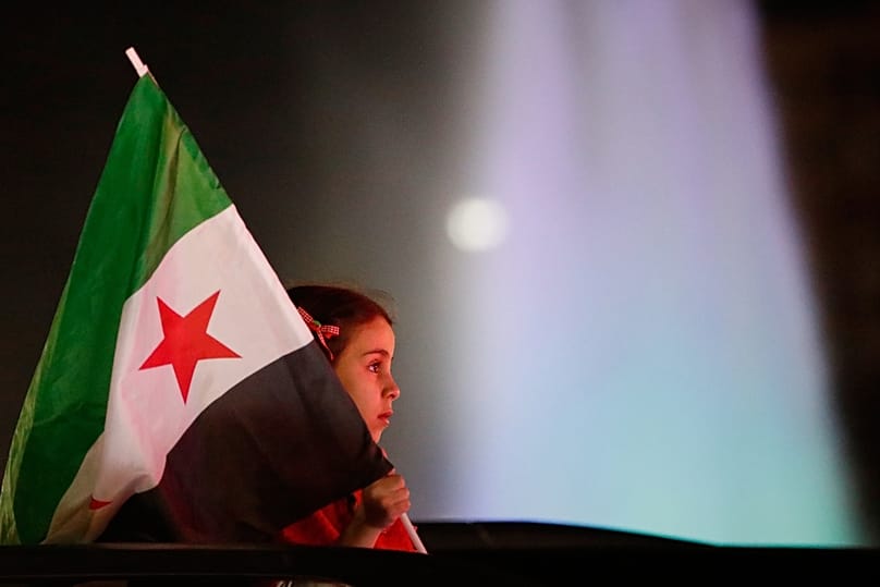  فتاة تحمل العلم السوري خلال احتفالات الذكرى الأولى للإطاحة بنظام بشار الأسد في دمشق، سوريا، في وقت مبكر من يوم السبت 6 ديسمبر/كانون الأول 2025.